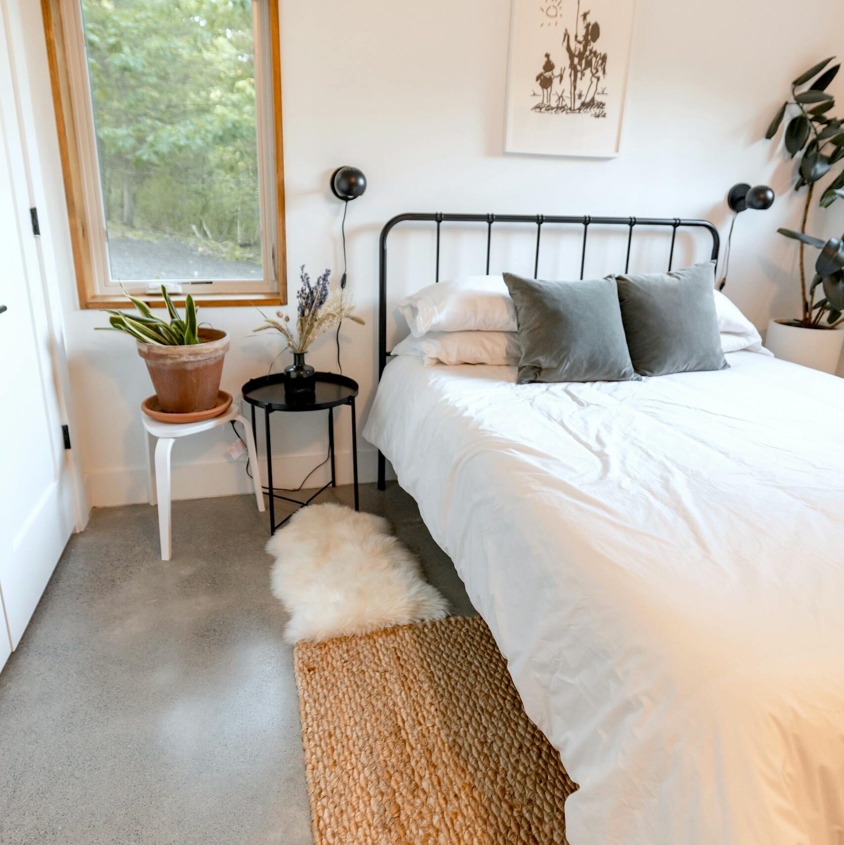 A bright and inviting bedroom featuring modern decor and lush plants.
